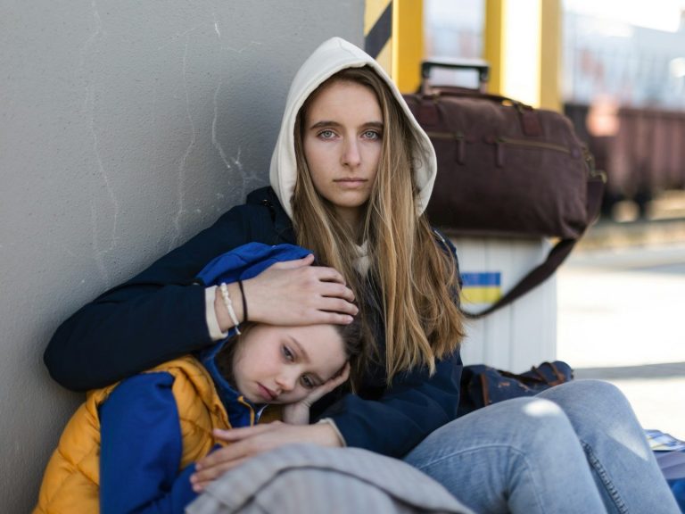 Sechs Jugendliche sitzen auf einer Mauer am Meer, während die Sonne untergeht.